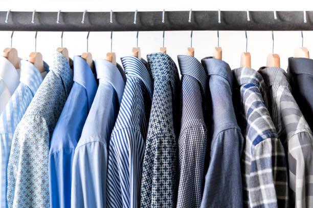 Row of men’s shirts in blue colors on hanger on white background